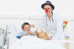Doctor in clown costume with boy in hospital