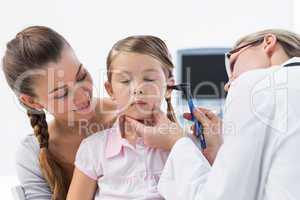 Girl being examined by doctor with otoscope