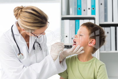 Doctor looking into the mouth of boy