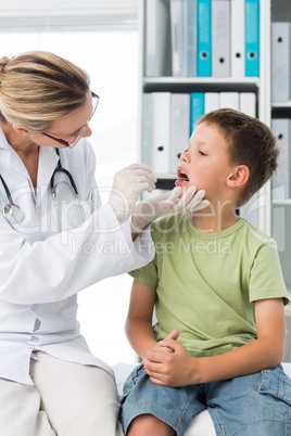 Doctor examining mouth of little boy