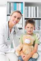 Friendly doctor with boy holding teddy bear