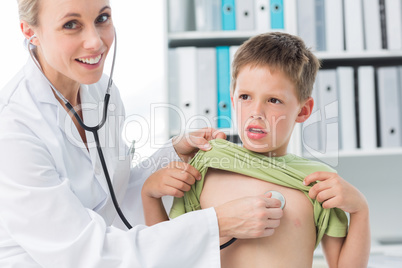 Confident doctor examining boy with stethoscope