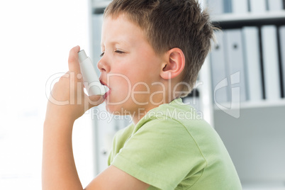 Boy using an asthma inhaler in clinic