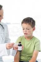 Doctor giving little boy syrup