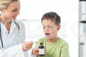 Doctor giving little boy cough syrup