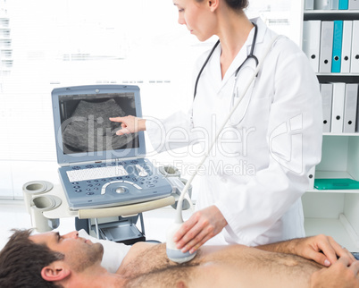 Cardiologist using sonogram on male patient