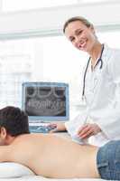 Doctor performing ultrasound scan on back of patient