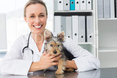 Happy female veterinarian holding puppy