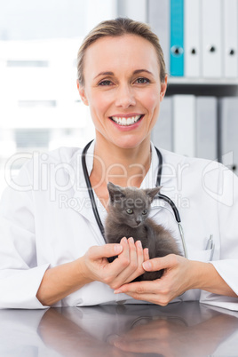 Happy female vet holding kitten
