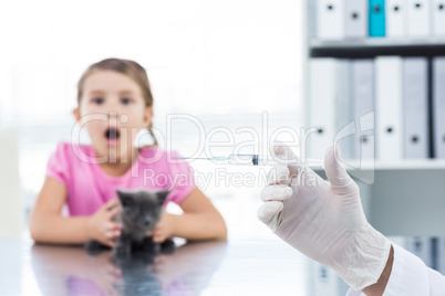 Vet holding syringe with socked girl holding kitten