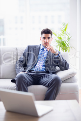 Serious businessman sitting on the couch looking at camera