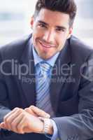 Businessman sitting checking his watch smiling at camera