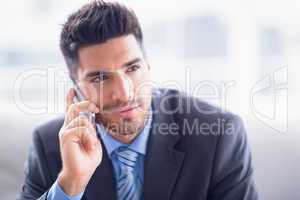 Handsome businessman sitting on sofa making a call