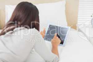 Young girl lying on her bed using her tablet