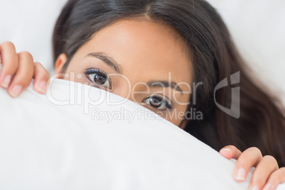 Pretty girl peeking from under the duvet