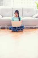 Pretty girl sitting on a floor using laptop