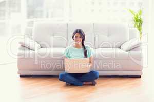 Pretty girl sitting on floor using laptop smiling at camera