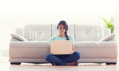 Pretty girl sitting on floor using her laptop