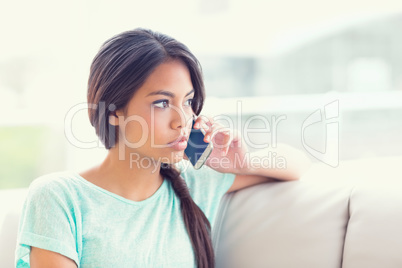 Pretty girl sitting on sofa making a phone call