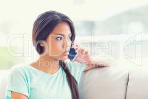 Pretty girl sitting on sofa making a phone call
