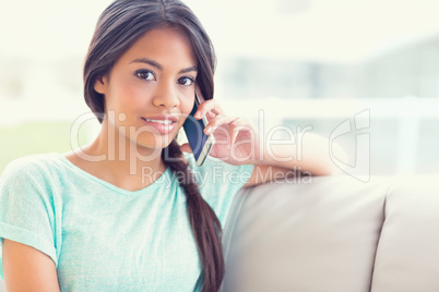 Smiling girl sitting on sofa making a phone call