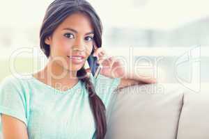 Smiling girl sitting on sofa making a phone call