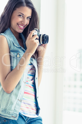 Stylish young woman taking a photo smiling at camera