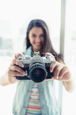 Happy young woman taking a photo at camera