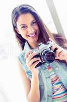 Smiling young woman holding her camera