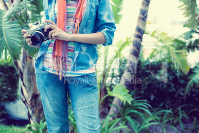 Woman wearing denim holding camera outside