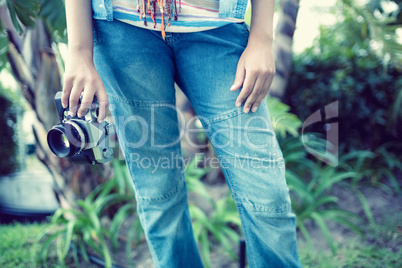 Woman wearing jeans holding camera outside