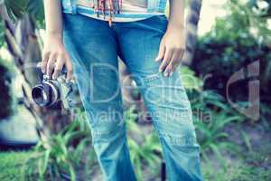 Woman wearing jeans holding camera outside