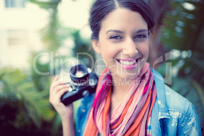 Cheerful brunette photographer standing outside smiling at camer