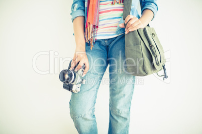 Woman in jeans holding camera and shoulder bag