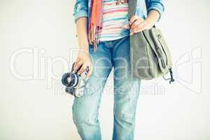 Woman in jeans holding camera and shoulder bag