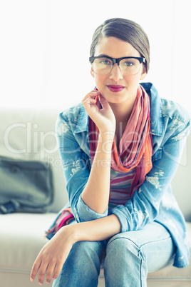 Young woman sitting on sofa smiling at camera