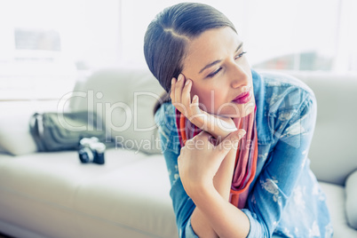 Pretty brunette sitting on sofa looking away