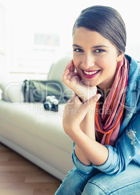 Young brunette sitting on sofa looking at camera