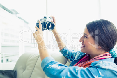 Young brunette sitting on sofa taking a selfie