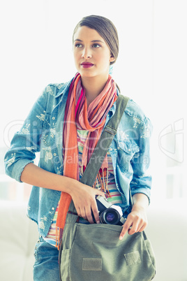 Young thinking woman taking camera from her bag