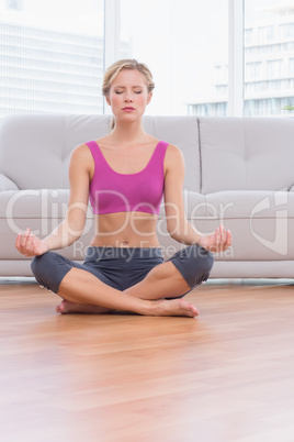 Fit blonde meditating in lotus pose