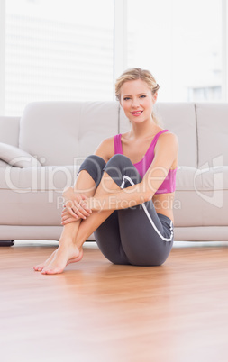 Slim blonde sitting on floor smiling at camera