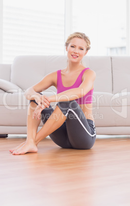 Athletic blonde sitting on floor smiling at camera