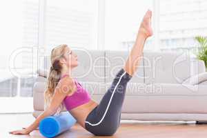 Fit blonde stretching on floor using foam roller