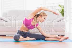 Fit blonde stretching on exercise mat