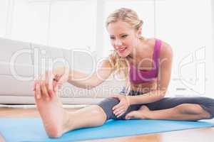 Toned blonde stretching on exercise mat