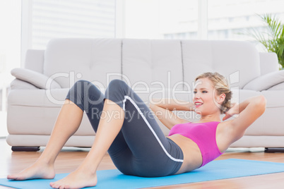 Slim blonde doing sit ups on exercise mat