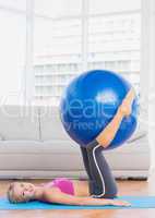 Smiling blonde holding exercise ball between legs