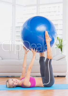 Happy blonde holding exercise ball between legs