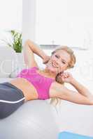 Smiling fit blonde doing sit ups with exercise ball